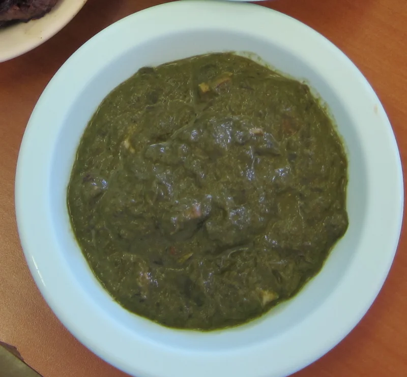 A bowl of squid lūʻau with cooked taro leaves.