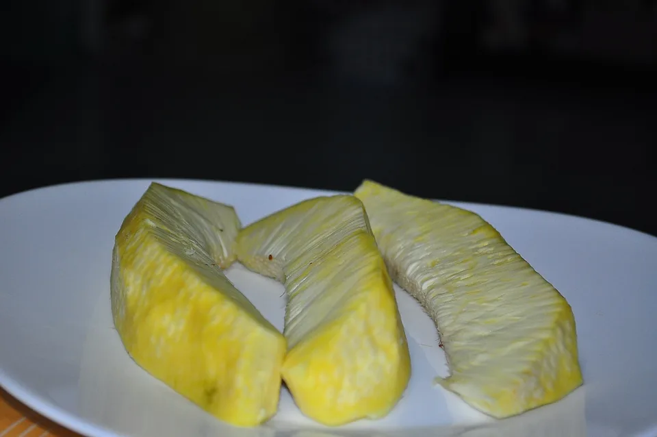 Slices of cooked breadfruit on a white plate, showing the pale yellow flesh.